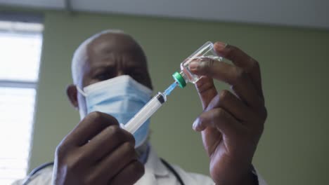 african american male doctor wearing face mask preparing injection