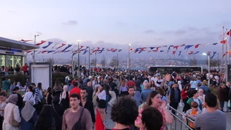 a large crowd of people gather in a city street with flags hanging above them