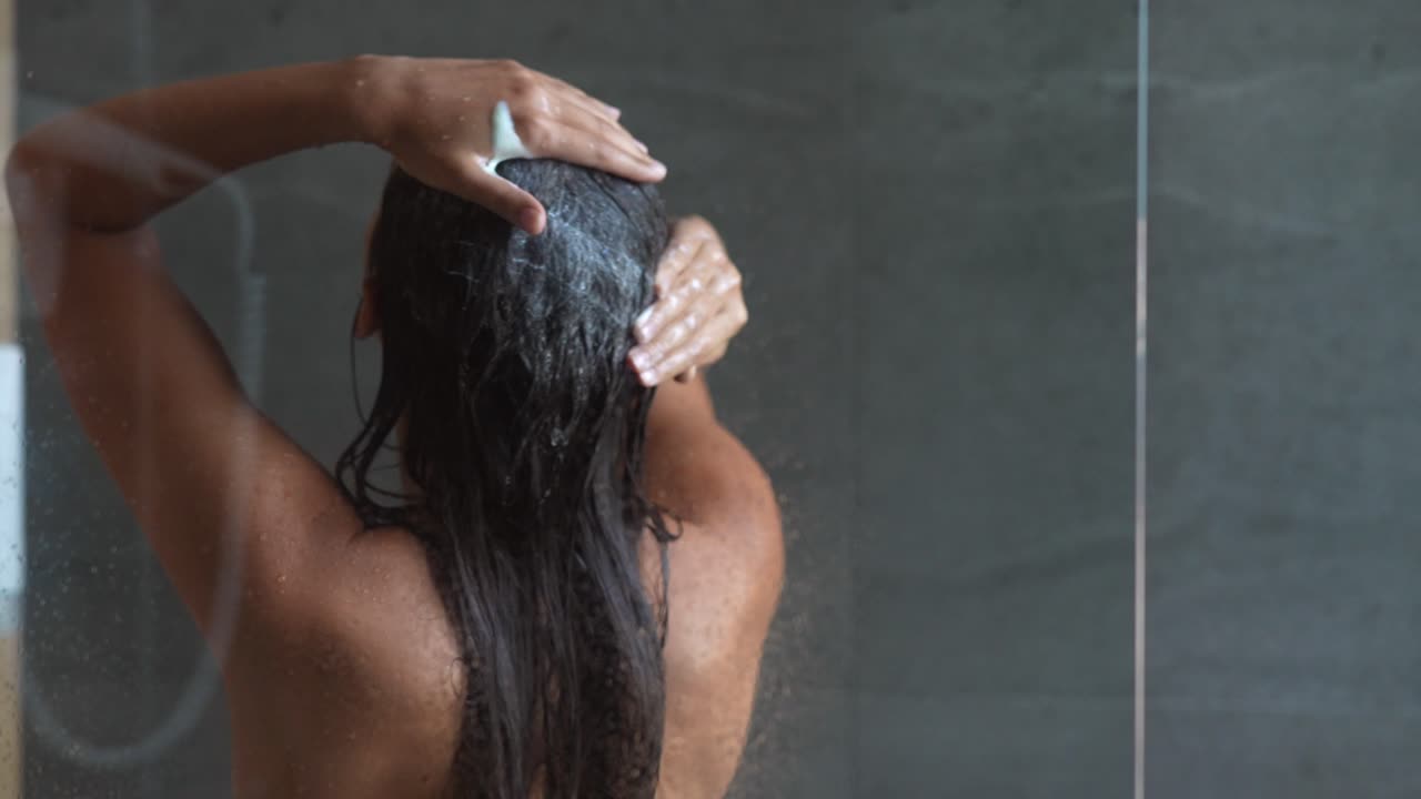 Donna che si lava i capelli sotto la doccia