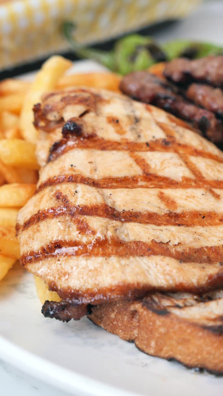 Primo piano di un piatto di pollo grigliato e carne con patatine fritte