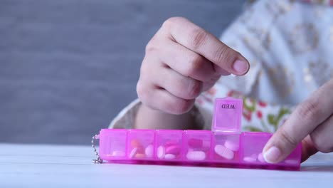 person taking medicine from a pill organizer