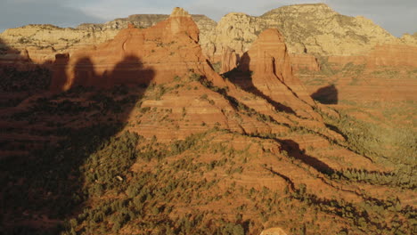 aerial: wild red rock mountain valley in sunlight at sedona, arizona - establishing drone flying forward shot