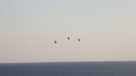 wide-shot-from-far-away-of-helicopters-in-aerial-show-with-sea-bottom