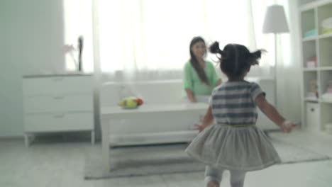 little girl running to embrace her pregnant mother sitting on the couch