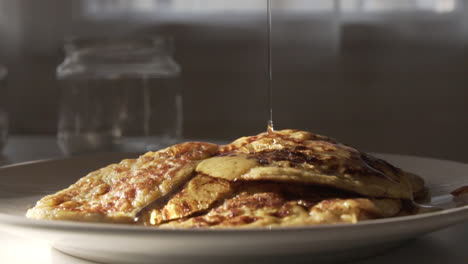 tasty breakfast, gluten free bio vegan pancakes on a plate in the kitchen, as pouring syrup on the top