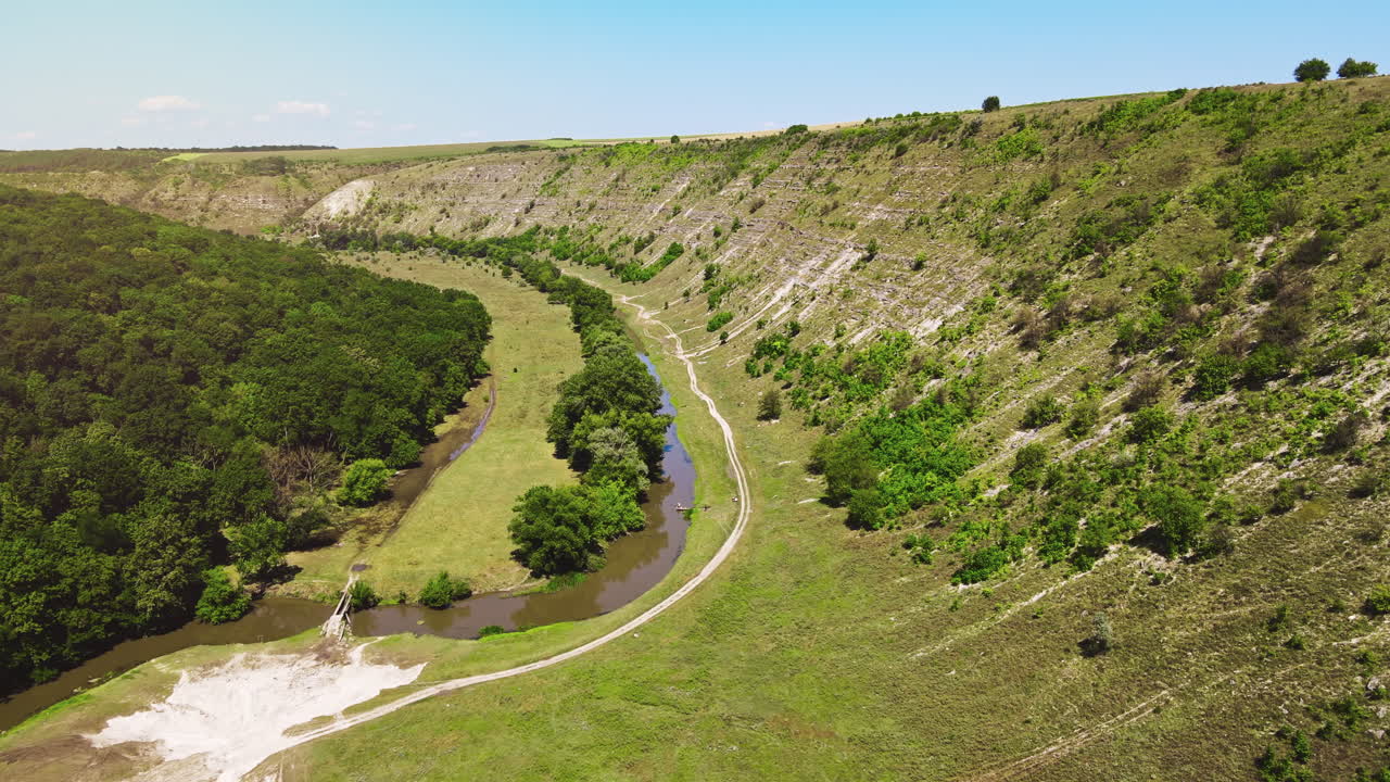 Aerial drone view of a valley with floating river, hill slopes and greenery around in Moldova