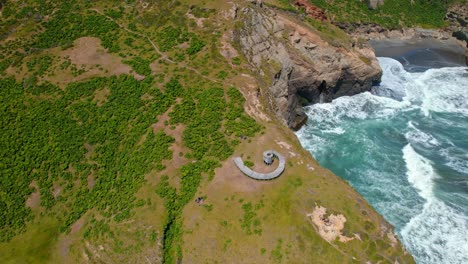 Aerial-wide-view-of-Muelle-del-Tiempo,-spiral-wooden-structure-at-Sea-shore-cliff,-Cucao,-Tepuhueico-park