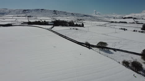 Winter-landscape-with-farms-and-snow-covered-open-field