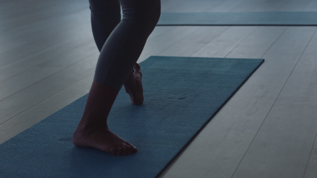 cerrar los pies de una mujer de yoga estirándose sobre una colchoneta de ejercicios preparándose para el entrenamiento matutino preparándose en el gimnasio al amanecer.