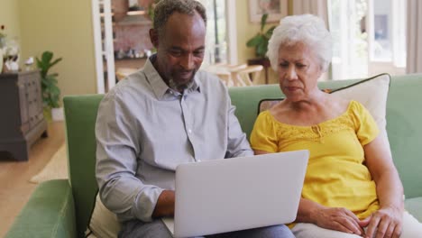 Senior-African-American-husband-and-mixed-race-wife-spending-time-and-working-at-home