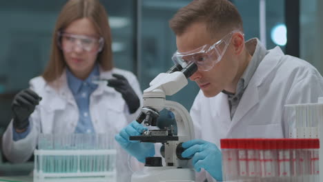 microbiological research of two experts in medical laboratory man and woman are exploring samples using test tubes and microscope apparatus