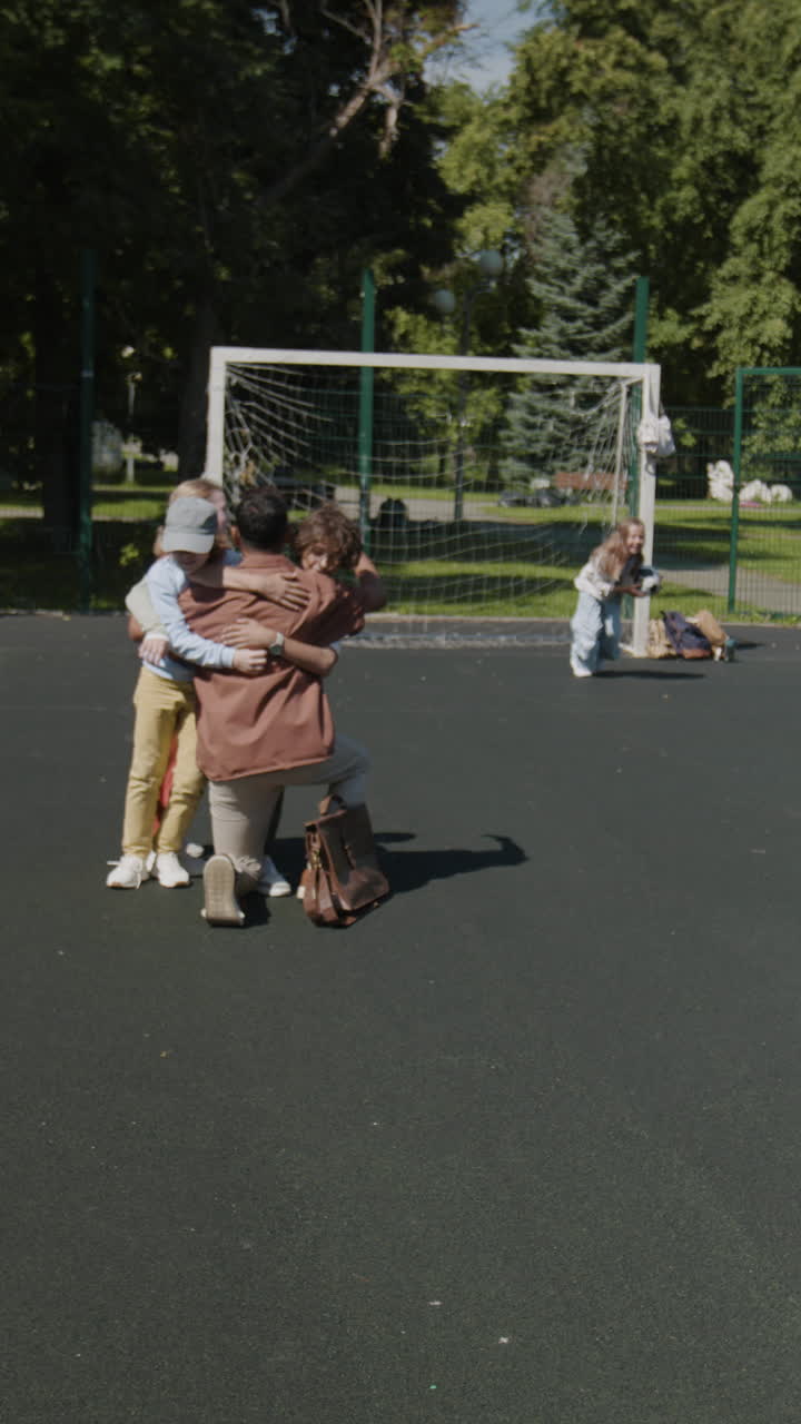 Adult and children share an emotional hug on a sports field