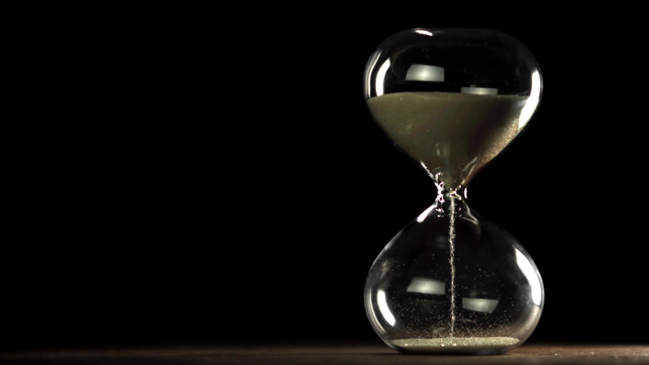 Hourglass with Sand Flowing on a Dark Background