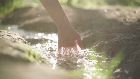 crop woman touching flowing water in river at night