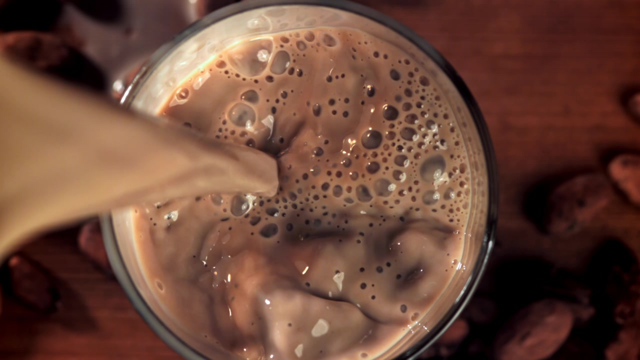 Versamento al rallentatore di latte al cioccolato in un bicchiere