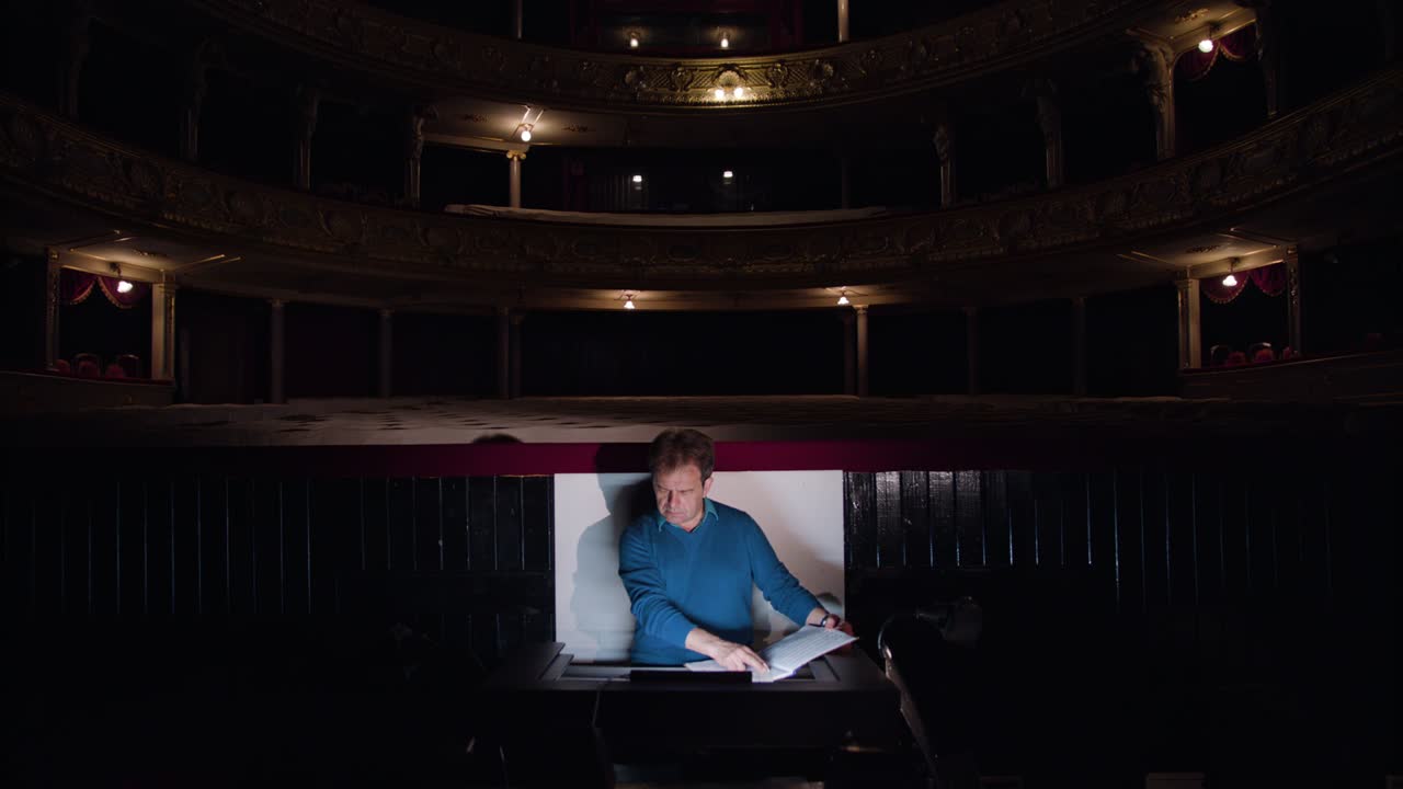 el director en un pozo de orquesta estudia partituras