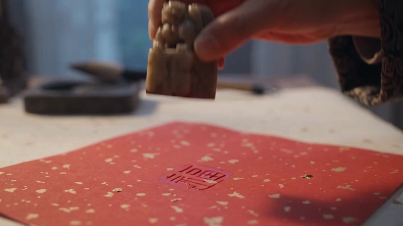 Mujer con vestimenta tradicional estampando papel rojo para el Año Nuevo Chino