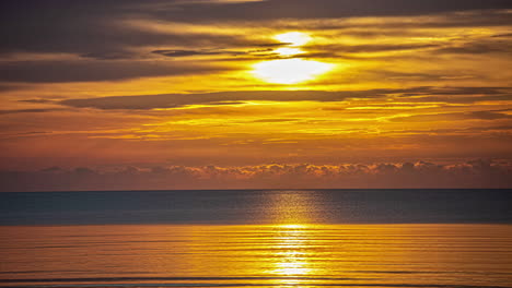 timelapse shot of majestic sunrise throught he clouds over the sea