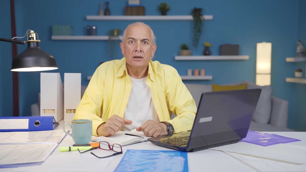 Home office worker old man looking at camera with excitement and feeling happy.
