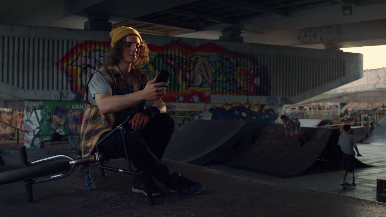 Man having video call on smartphone at skate park. Handsome guy talking online.