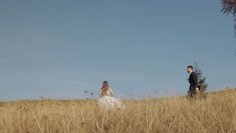 Newlyweds.-Caucasian-groom-with-bride-running-on-mountain-slope.-Wedding-couple