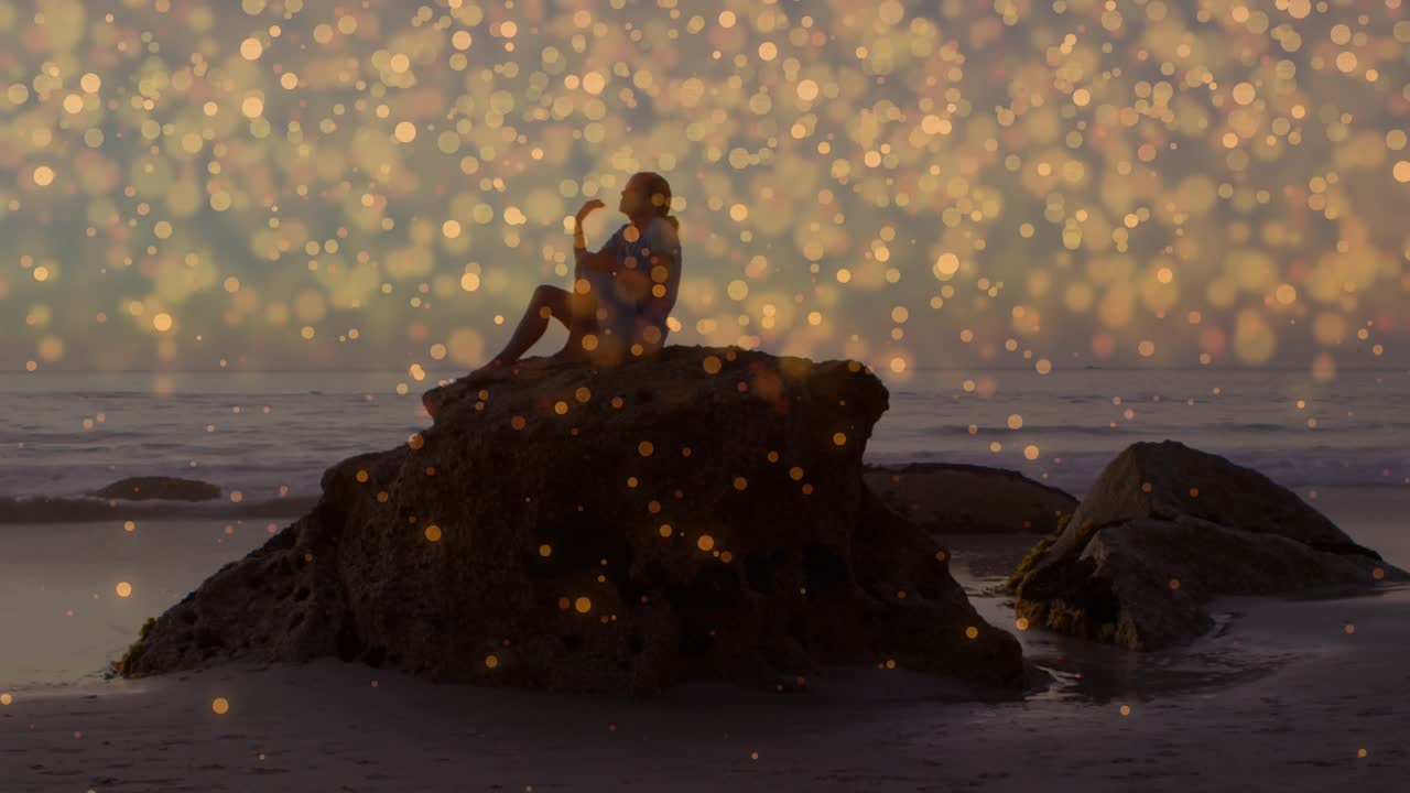 Woman approaching rock at sunset, crouching while golden particles drifting for wellness