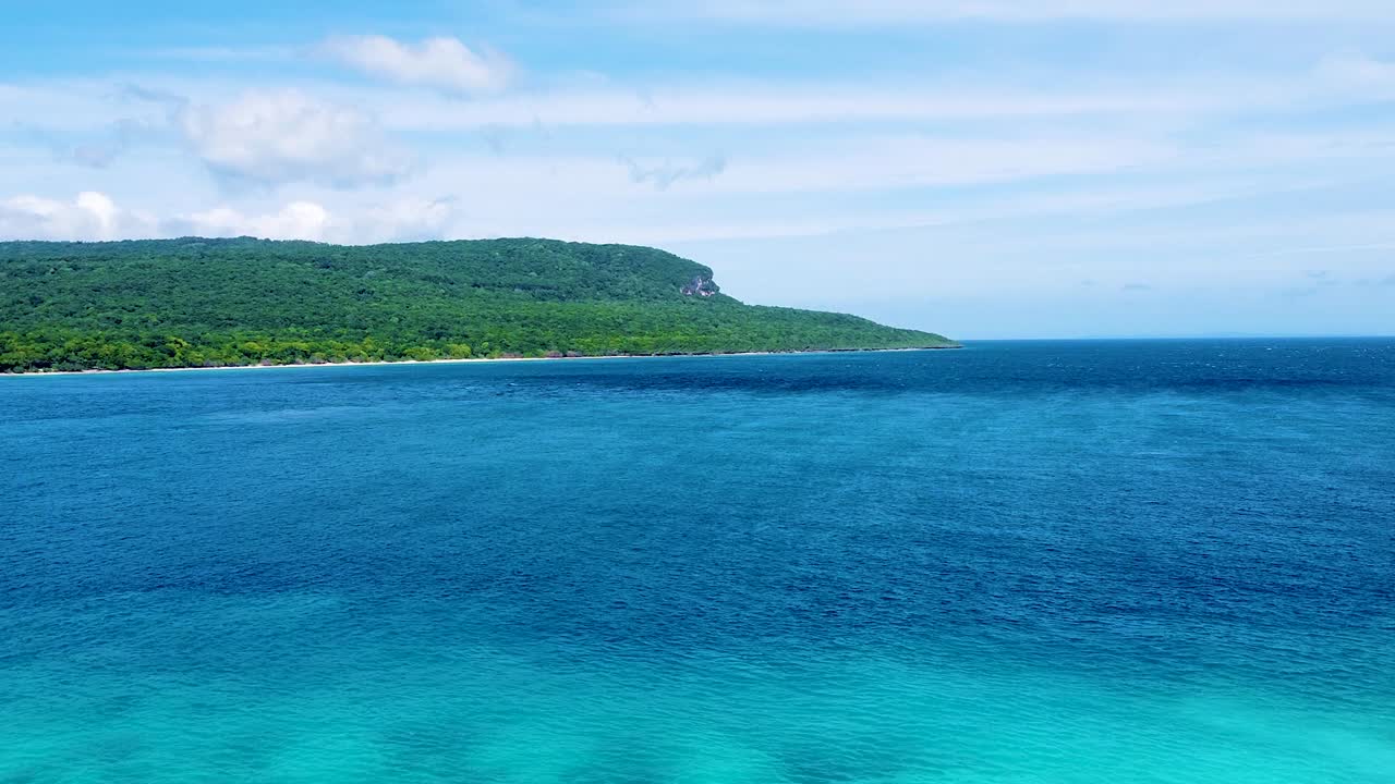 Aerial view rising over tropical island of Timor-Leste with green forest trees and turquoise ocean water in Southeast Asia