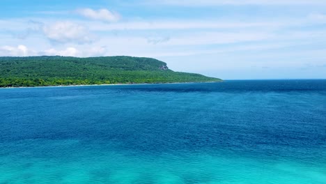 aerial view rising over tropical island of timor-leste with green forest trees and turquoise ocean water in southeast asia