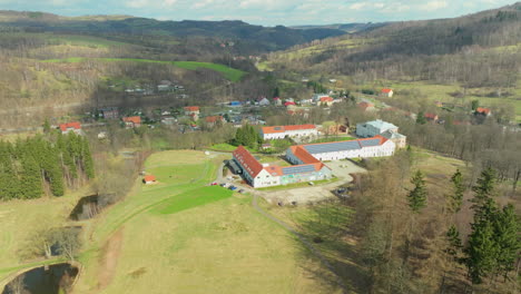 Aerial-view-of-modern-hotel-with-solar-panels-on-roof-in-scenic-hilly-of-Poland,-Europe