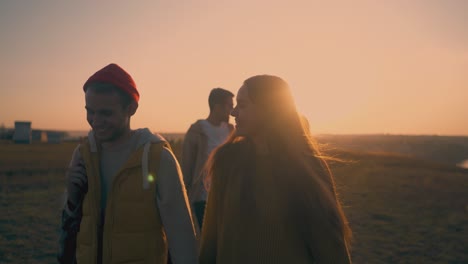 happy couples walk along hill to campsite at sunset