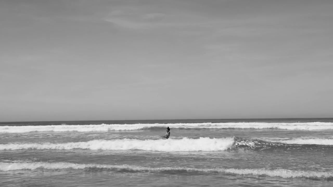 Donna in piedi tra le onde dell'oceano in bianco e nero