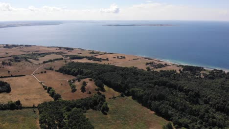 Aerial-view-of-the-coastline-of-Sejerøbugten-with-hills,-fields-and-ocean