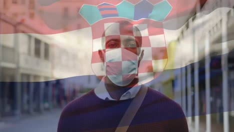 Animation-of-flag-of-croatia-waving-over-african-american-man-wearing-face-mask-in-city-street