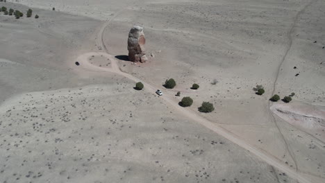 drone shot of white and black vehicle on desert road by sandstone tower, dry landscape of utah usa and kodachrome basin state park