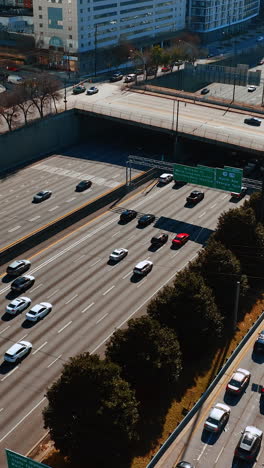numerous cars run by the multilane road in downtown of atlanta on daytime. sunny panorama of the city from top. vertical video