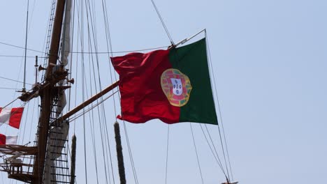 fotografía de mano de la bandera portuguesa en un barco en oporto durante un día de viento, de cerca