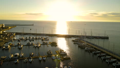 impresionante puesta de sol sobre el puerto deportivo de gdynia lleno de veleros mientras la luz del sol se refleja en las tranquilas aguas del océano, antena de drones