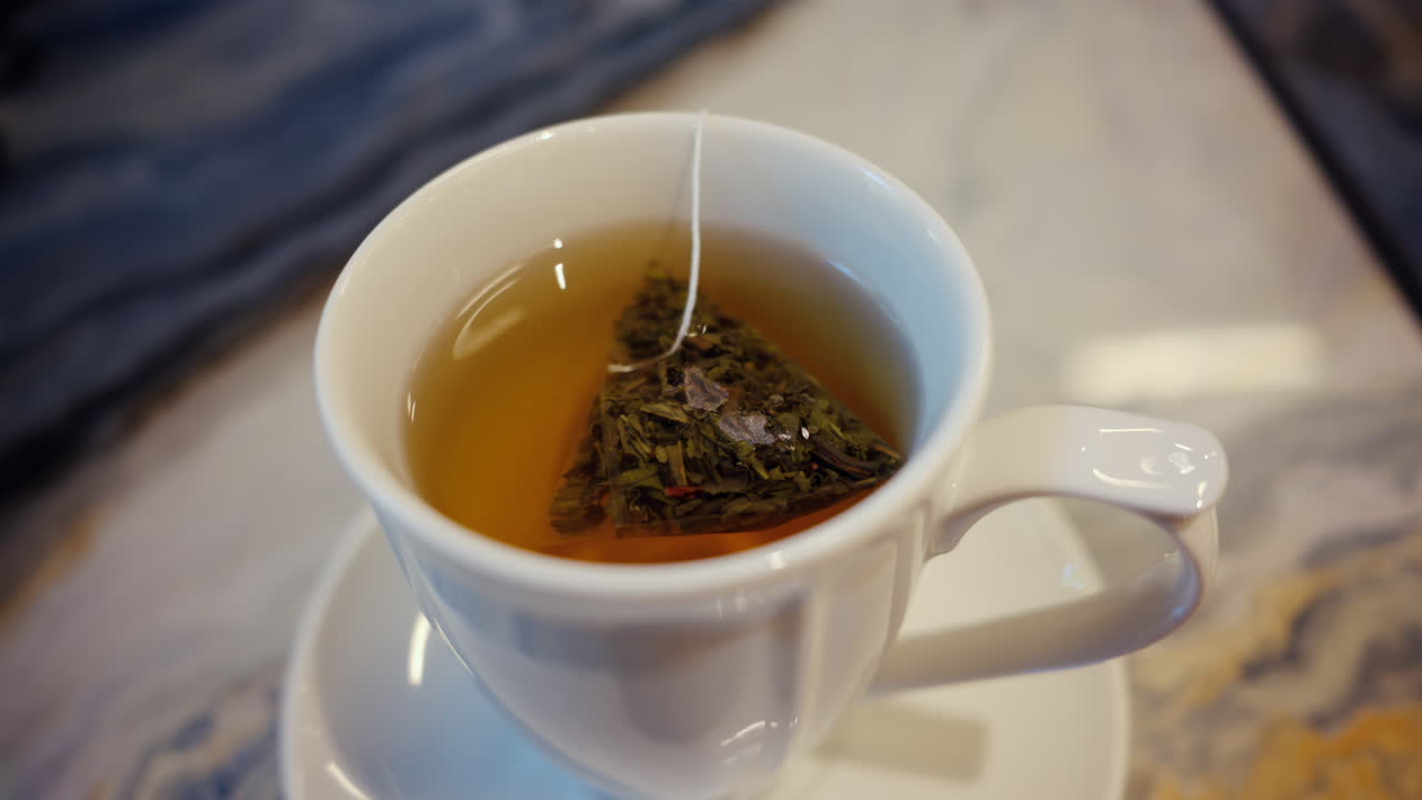 Close up of a white cup of tea standing on a marble table