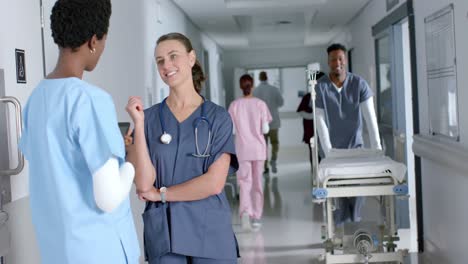 Happy-diverse-female-doctors-talking-in-hospital-corridor,-slow-motion