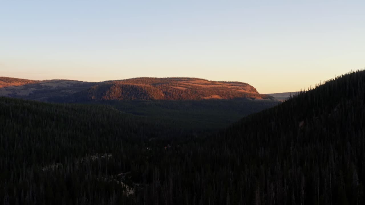 dolly out paisaje toma aérea de un cañón en el bosque nacional uinta wasatch cache en utah con una carretera debajo rodeada de pinos y montañas rocosas durante una vívida puesta de sol de verano