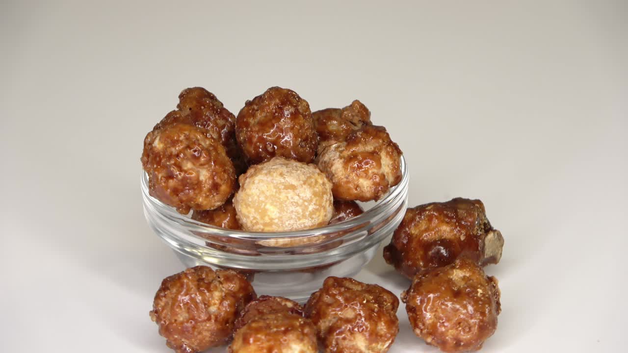 색 배경에 작은 그에서 회전하는 많은 캔디 매카다미아 견과류의 루프 가능한 영상입니다.