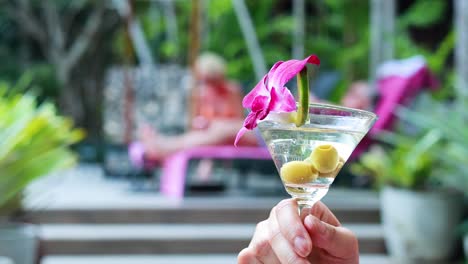 un vibrante martini con aceitunas y una guarnición de orquídeas se disfruta a la orilla de la piscina, capturando una atmósfera relajada y tropical