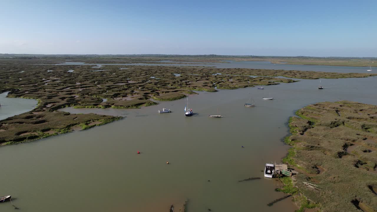 yate navegando por el río blackwater con marismas en el puerto deportivo de tollesbury, essex, reino unido