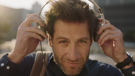 close up portrait of cool handsome caucasian man puts on headphone listening to music looking happy at camera enjoying urban lifestyle