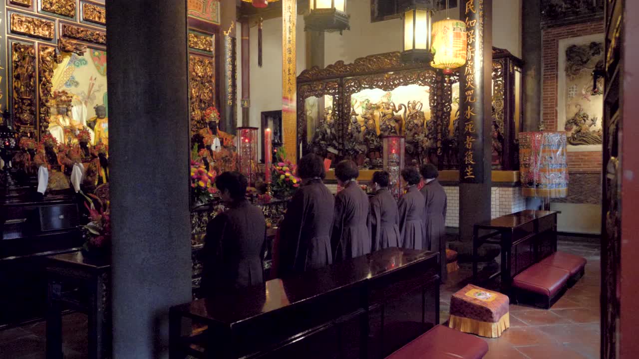 Slow motion shot of six women praying at Dalongdong Baoan Temple in Taipei, Taiwan