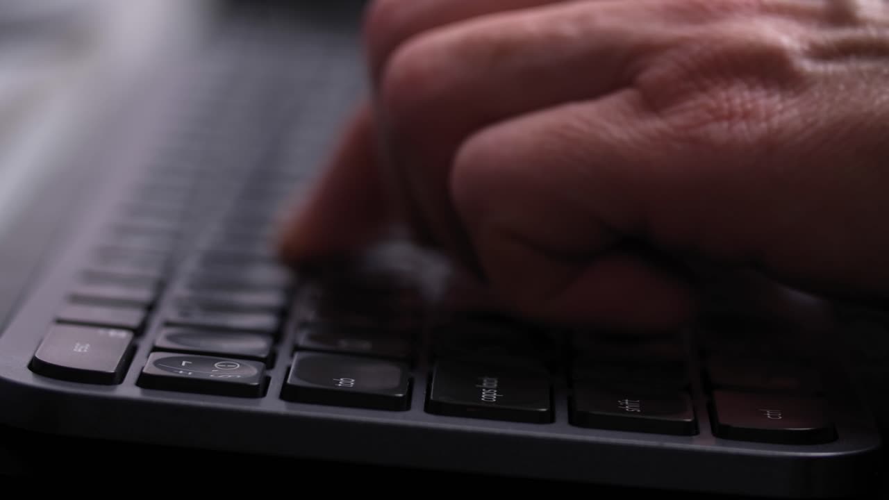 escribiendo a mano en un teclado de computadora negro, vista lateral de cerca
