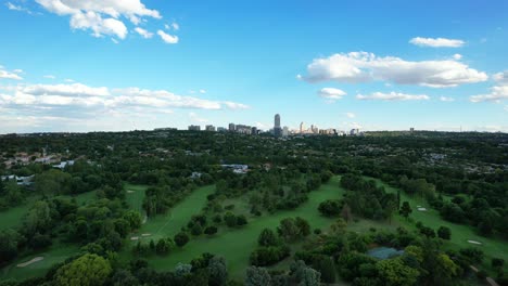 Grüner-Golfplatz-Mit-Skyline-Von-Sandton-In-Johannesburg-Tagsüber,-Luftaufnahme