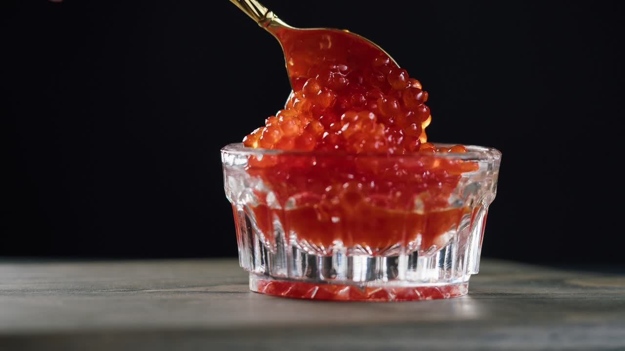 Prelevare caviale rosso fresco da una ciotola di vetro