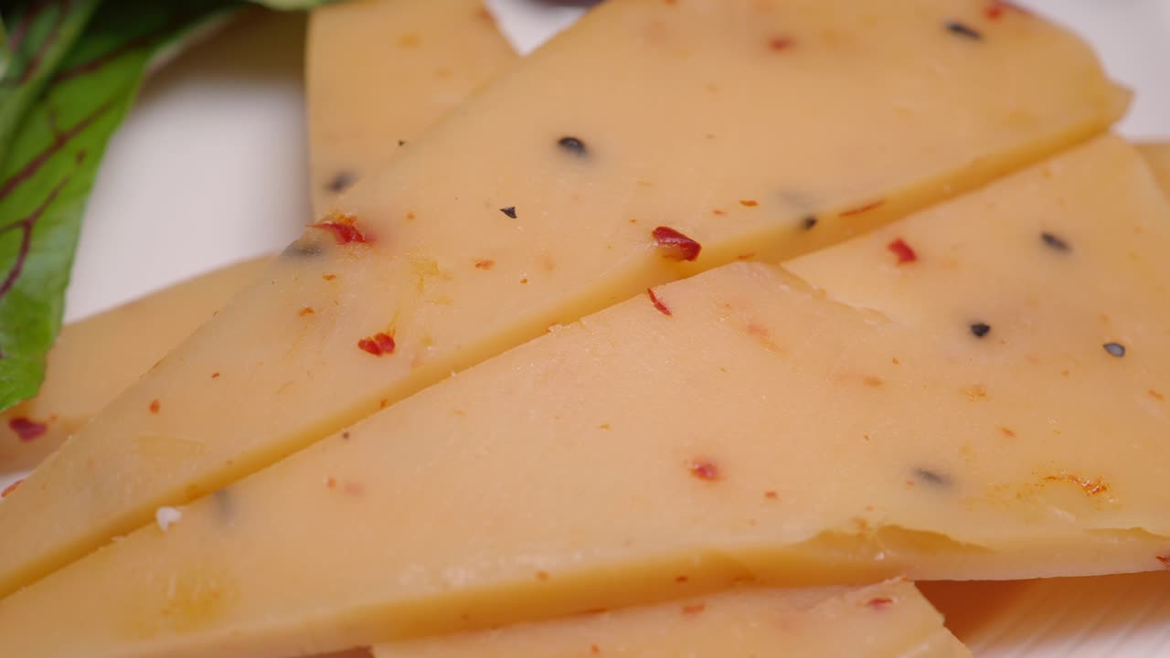 Fette di formaggio gourmet con scaglie di peperoncino rosso e grani di pepe nero