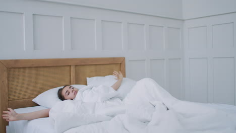 una mujer joven se despierta en la cama por la mañana sonriendo levanta las manos